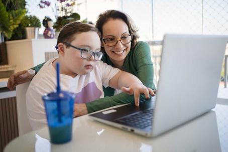 Mother helps her special needs daughter to use a laptop